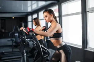 “A fit young woman performing cardio exercise on an elliptical machine, showcasing an effective and accessible workout for staying fit at home.”